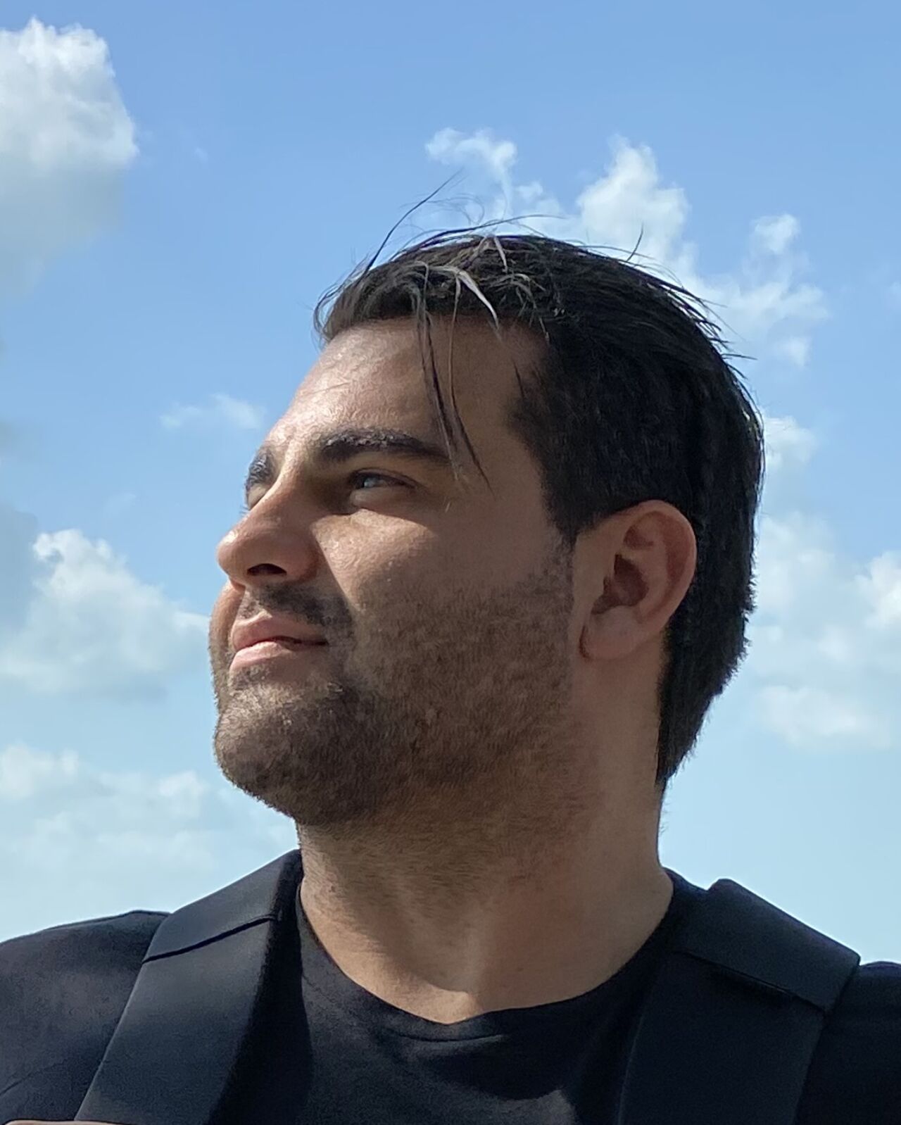 Real photo of Richard outdoors on a sunny, windy day, looking out towards the sea